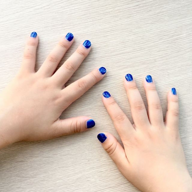 青色のマニュキュアを塗っている子供の手